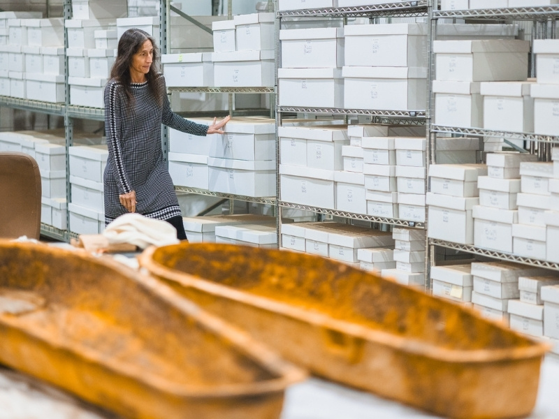 Dr. Jennifer Mack showcases hundreds of boxes of artifacts and remains discovered since the start of the Asylum Hill excavation project, which began in 2022, with each box carefully labeled and organized.