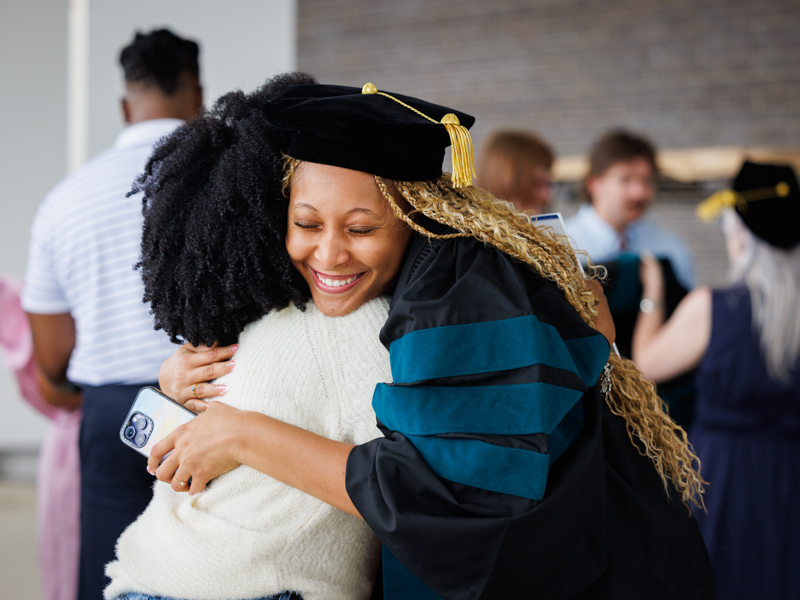 Brianna White, PhD physical therapy graduate, receives a congratulatory hug from friend Bianna Hamlin.