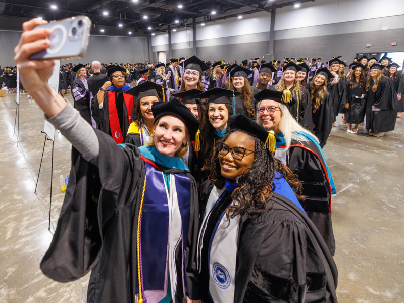 Elizabeth Carr, chair of dental hygiene takes a selfie with graduates and staff in the School of Dentistry.