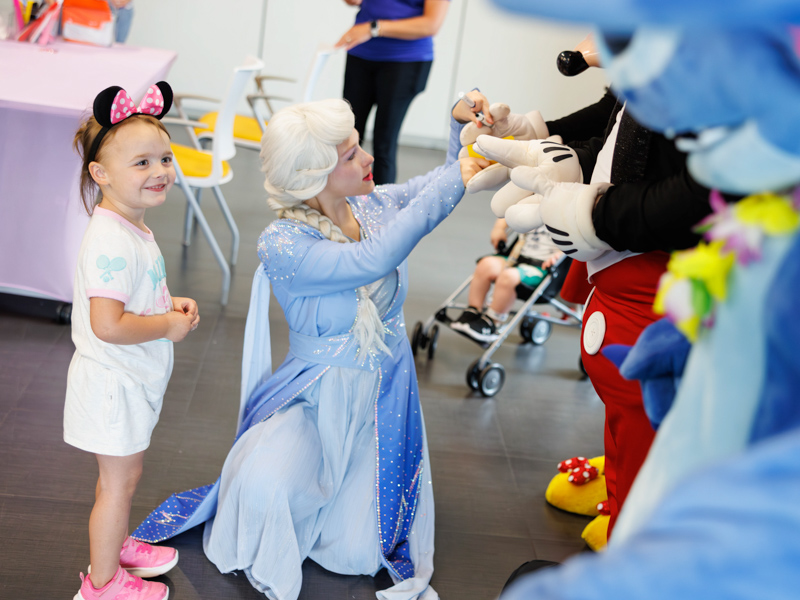 Jamie Upton of Little Rock meets Mickey Mouse and Stitch accompanied by her friend Princess Elsa at Disney Day hosted in the Sanderson Tower Community Room located in the children's hospital.