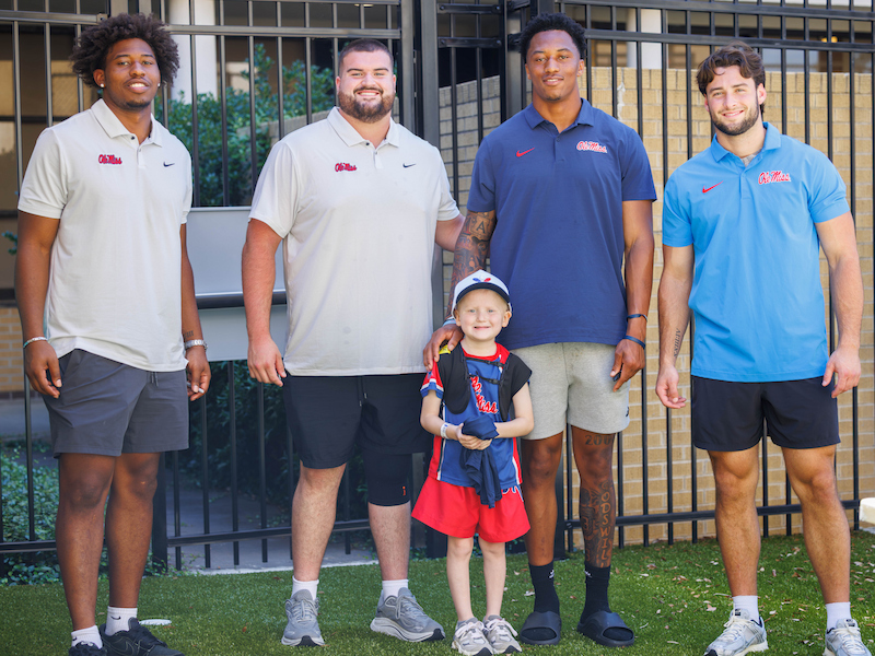 University of Mississippi football players, from left, Blake Purchase, Troy Everett, Jonathan Maldonado and Luke Ferrelli pose with Ledger Smith, 6, of Brookhaven during a visit to Children's of Mississippi