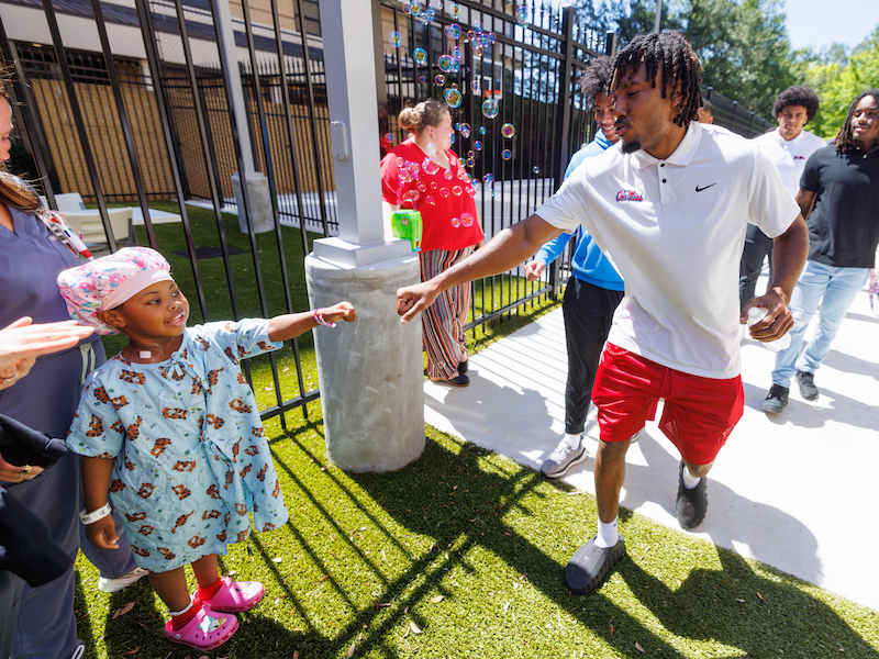 Ole Miss cornerback Jaylon Braxton gets a fist bump from Tzuri Elmore during a visit from the University of Mississippi football team at Children's of Mississippi.