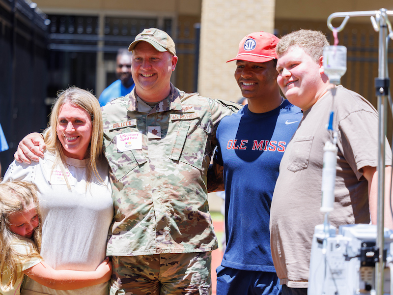 Ole Miss quarterback Trinidad Chambliss poses for a photo with patients' family during a team visit to Mimi's Playground at Children's of Mississippi.