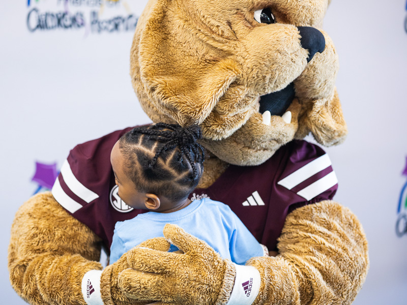 Kaidyn Bruce, 2, hugs Bully Bulldog at Tailgating with Friends in the Sanderson Tower community room.