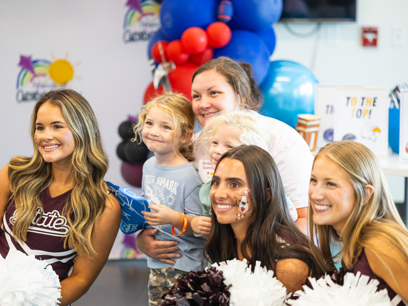 Graham and Dustin Osborne, 3, of Philadelphia pose with their mom and Mississippi State University cheerleaders at Tailgating with Friends.