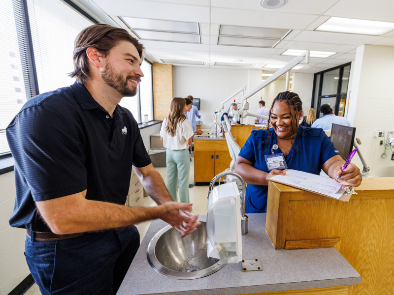 Leisia Summers, administrative assistant, checks first-year dental student Cole Davidson's handwashing skills, which is a part of orientation week. Jay Ferchaud/ UMMC Communications 