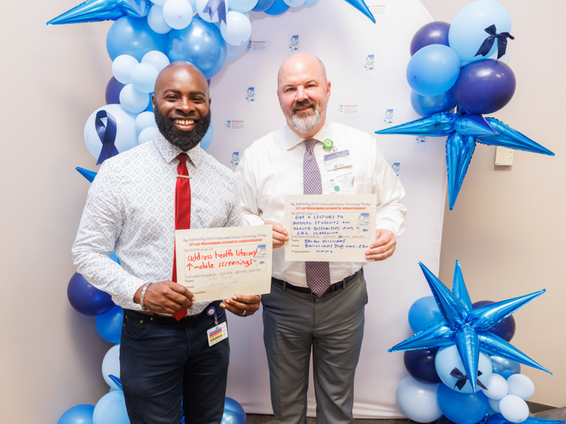 Dr Justin Turner, left, assistant professor of preventive medicine, and Dr. Brian Williams, associate professor of preventive medicine, show their pledges during a breakout session of the 80x 2030 launch by the Mississippi Colorectal Cancer Roundtable.