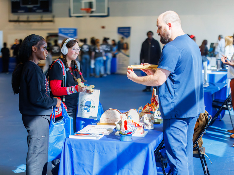 Pelahatchie High School tenth graders Lela Jordan, left, and Landry McMillan listen as Dr. Matthew Yeomans explains parts of the skeletal system during Discovery Day
