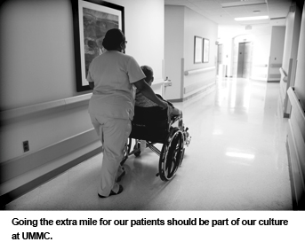 Hospital staff member pushes patient in wheelchair.