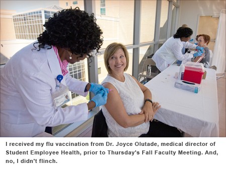 Dr. Joyce Olutade gives Dr. LouAnn Woodward a flu shot.