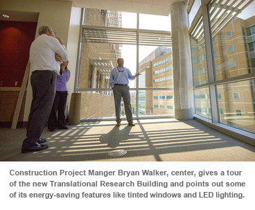 Construction Project Manger Bryan Walker, center, gives a tour of the new Translational Research Building and points out some of its energy-saving features like tinted windows and LED lighting.