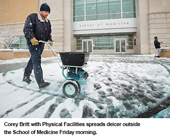 Corey Britt with Physical Facilities spreads deicer outside the School of Medicine Friday morning,
