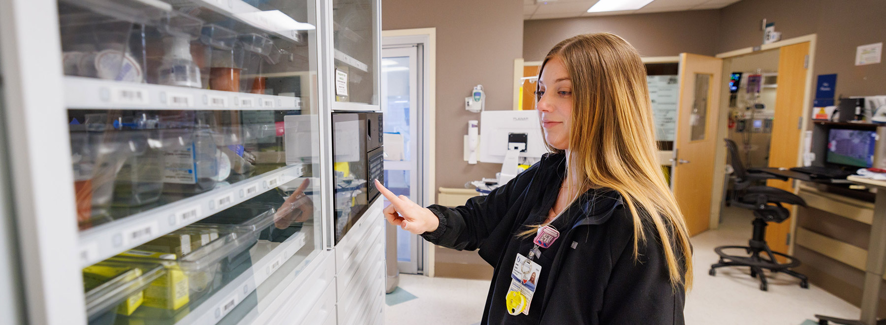 A pharmacy resident opening a medicine cabinet.