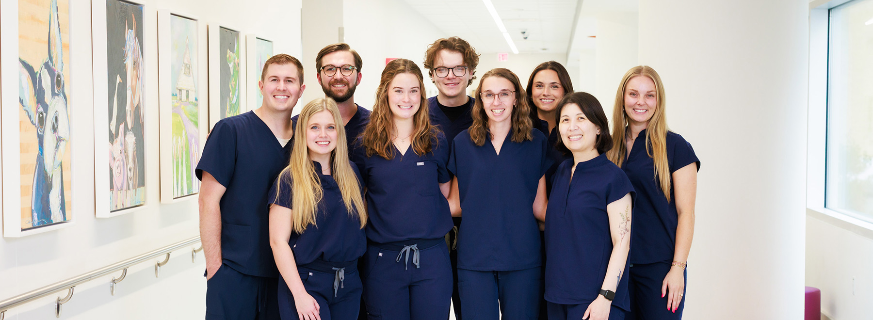 Group of nine UMMC-based pharmacy resident pose for a photo in a hospital corridor.