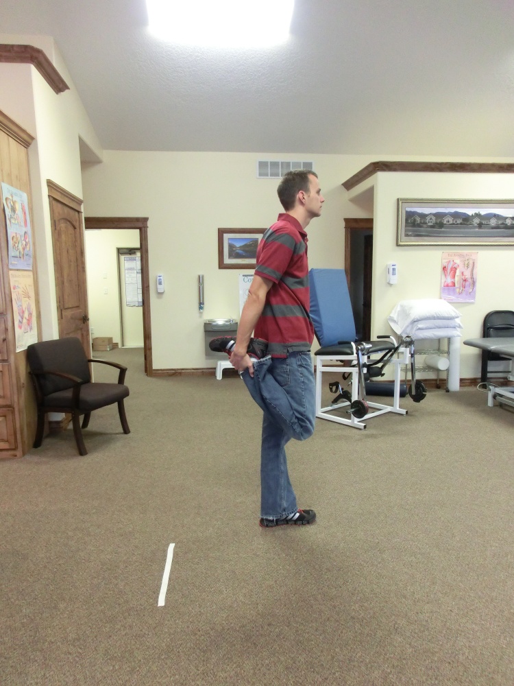 Man doing dynamic ankle grab exercise.