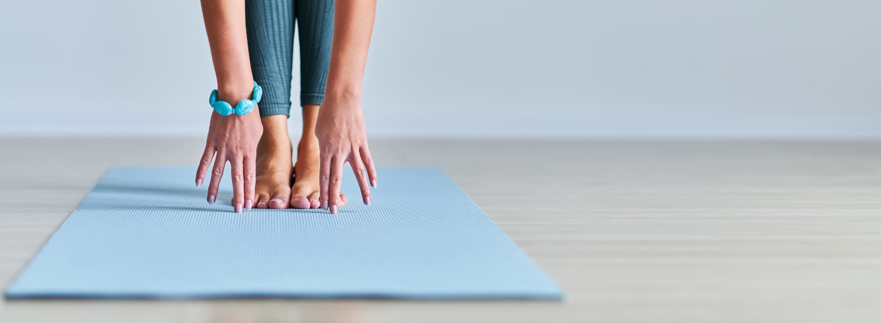 closeup of hands and feet of woman performing yoga pose while standing on a mat