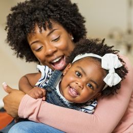 A smiling mother holds a smiling child.