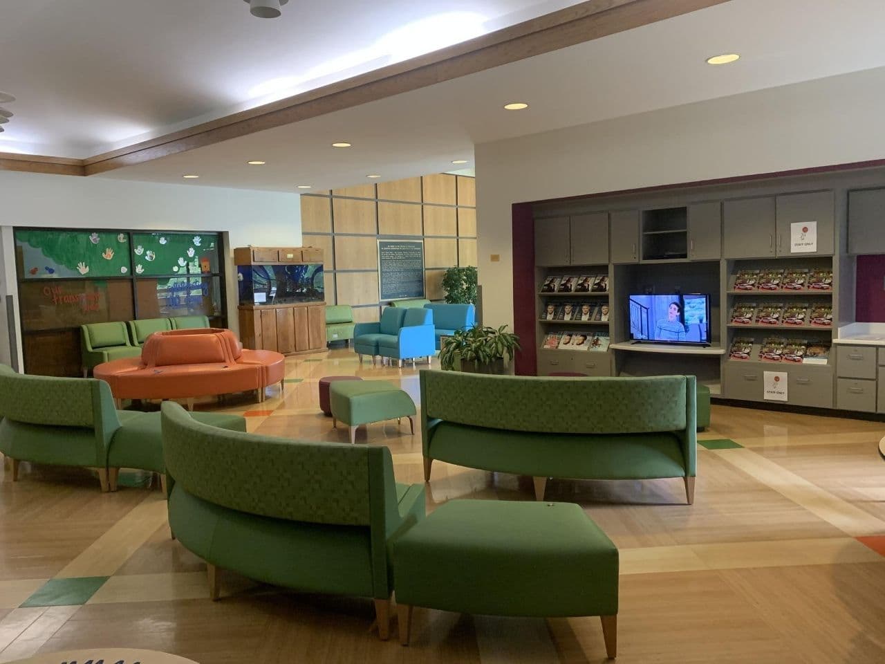 The waiting room has lots of colorful seating with orange and green couches and ottomans.