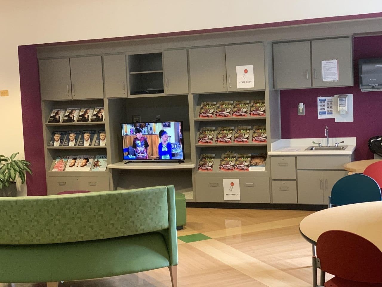 The media wall in the waiting room has a large TV and lots of magazines with a sink.