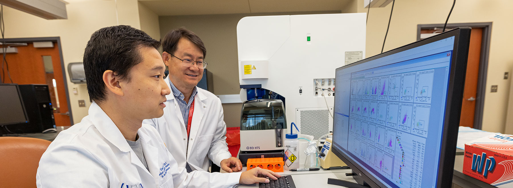 Researchers in lab viewing computer screen.