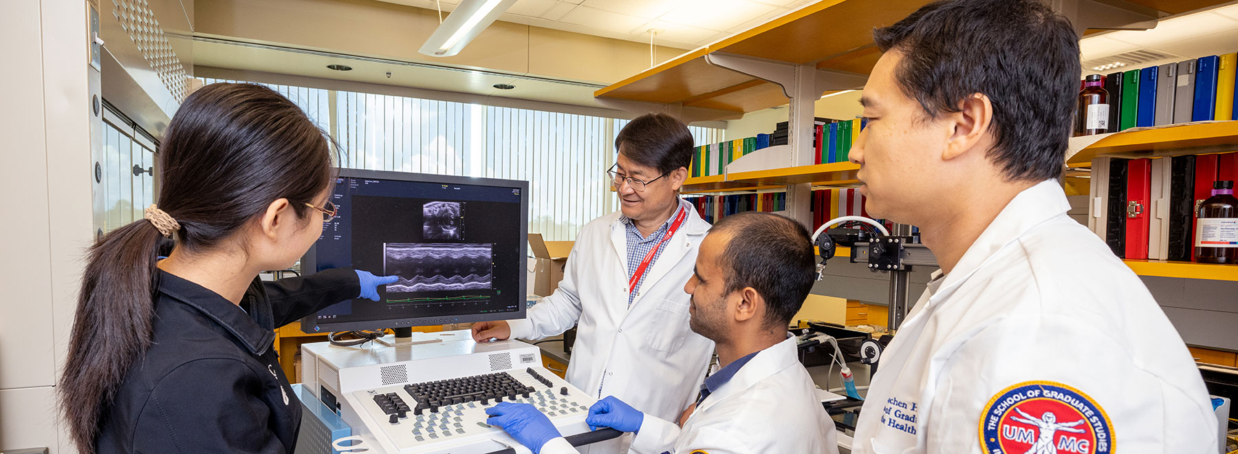 Researchers in lab viewing computer screen.