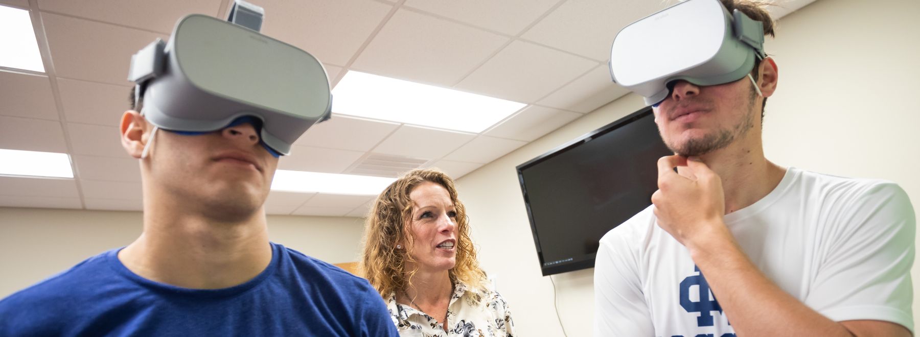 Dr. Reneker directs two male patients in extended reality physical therapy.