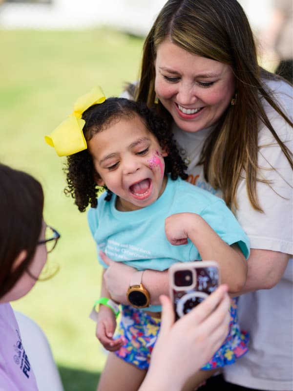A girl laughs and smiles as she sees her face paint at Family Fun Day 2026.