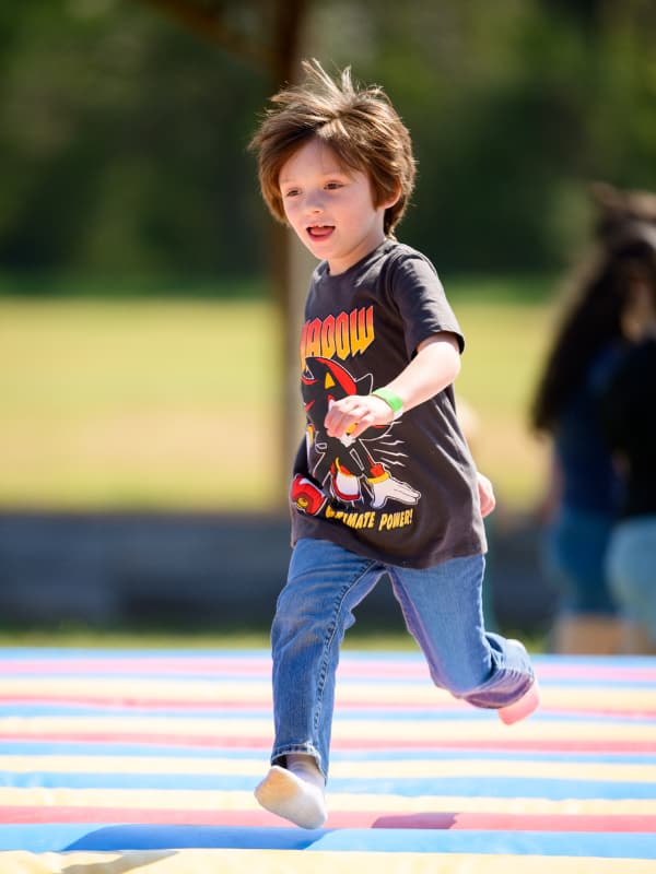 A boy with a green wrist band plays on a bouncy toy at Family Fun Day 2026.