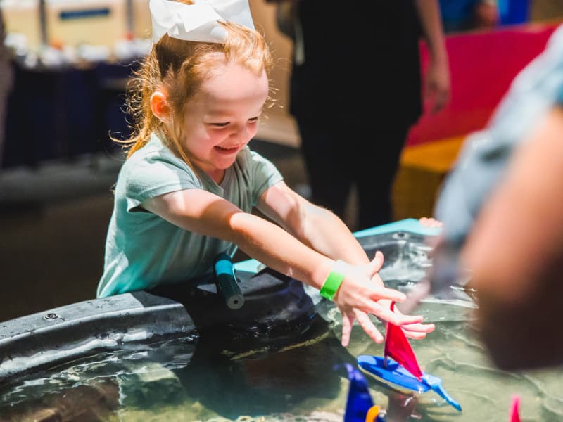 A young girl plays with a sailboat at Family Fun Day