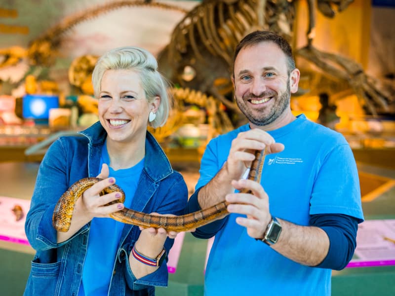 Dr. Laura Humphries and Dr. Ian Hoppe holding snakes at Family Fun Day