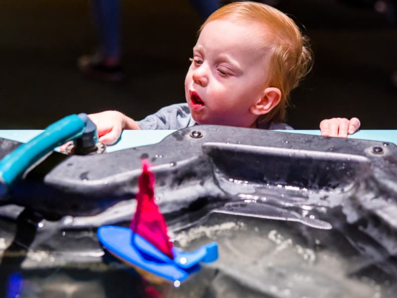 A toddler looks at a sailboat at Family Fun Day
