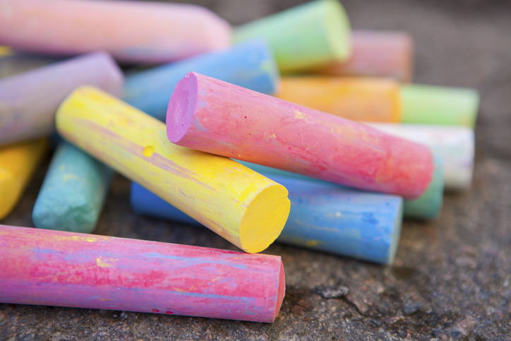 Closeup of multicolored pieces of chalk on the ground.