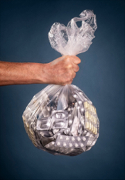 Hand holding a plastic bag with many medicines.