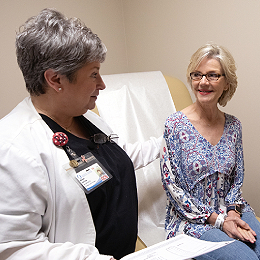 Female patient smiles at nurse in hospital room.