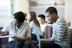 Students sitting in a lounge with laptop computers.