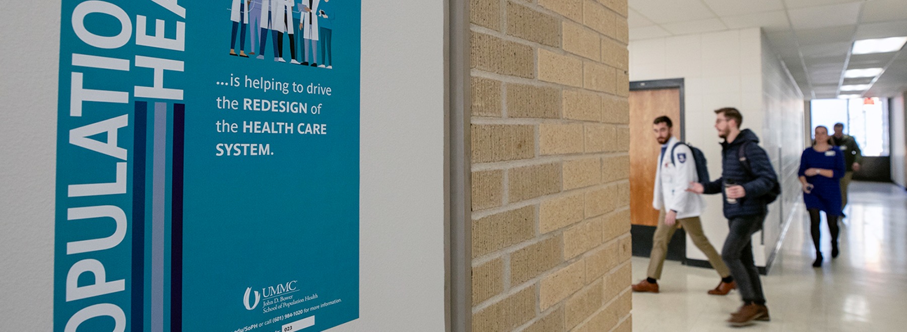 Population Health Bingo sign in hallway with person walking down the hall in the background.