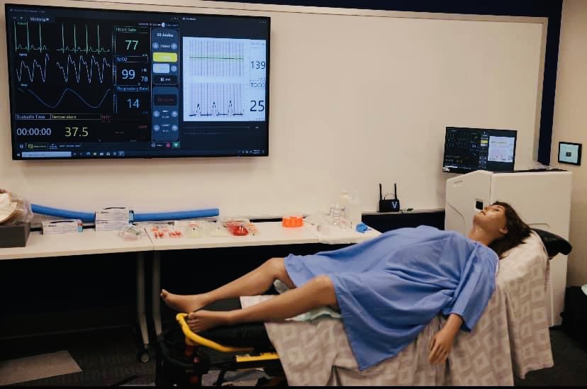 Neonatal simulation room with mannequin of pregnant patient on a gurney.