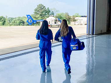 Two Children Transport Services staff members leaving a hangar to enter a helicopter.