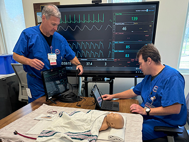PARTNER Conference participant reviewing data on a monitor for a dummy patient.
