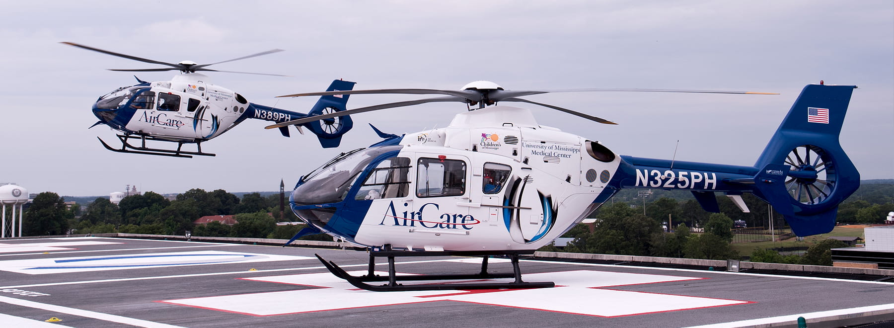 Two AirCare helicopters with one in flight Two AirCare helicopters with one in flight