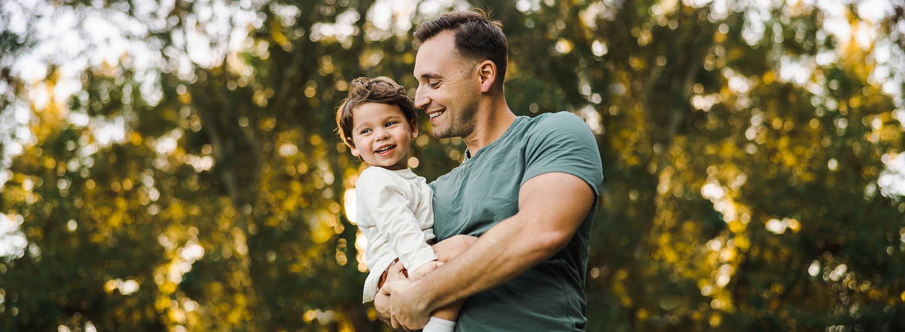 Person holding child while smiling.