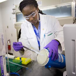 Researcher extracting samples from container.