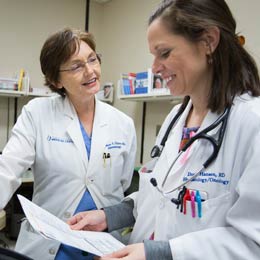 Two smiling doctors review printed lab results.