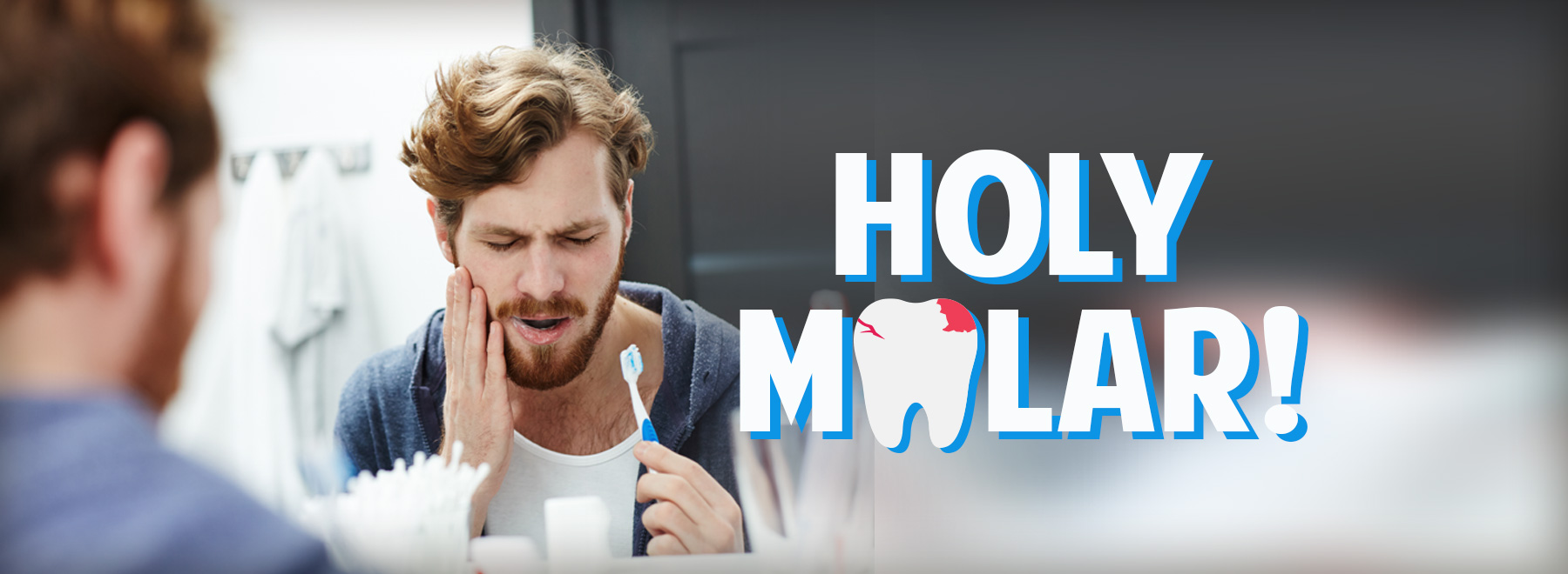 Image of Red haired male holding his face from tooth pain while brushing his teeth