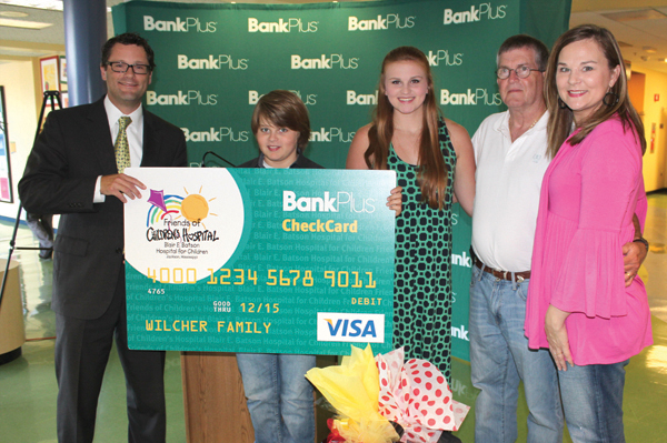 Rob Armour, left, presents Grant Wilcher with a $1,000 Friends of Children’s Hospital CheckCard. Other members of the Wilcher family are, from left, sister Alex, dad Jimmy and mom Lori. Older brother Bo is not pictured.