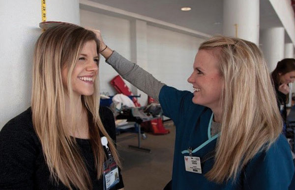 OT student Sydney Sisson, right, gauges the height of medical student Haley Houghton at the BMI station.