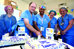 Dr. Edwin Harmon, second from right, professor of pediatric urology, and Vicki Rhymes, center, shift supervisor, cut the 10th anniversary cake while, from left, Shannon Furrer, RN, Angela Smith, surgical tech and Ashley Taylor, RN, look on.