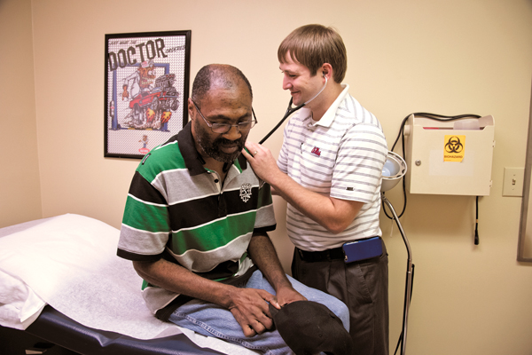 In one of his father’s old examining rooms, Dr. Sam Holdiness takes his time with patient Rickie Parks.