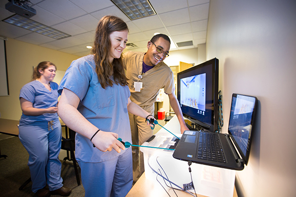 Mayes instructs Taryn Green, M4, on his device, while Kim Zachow, M3, observes.