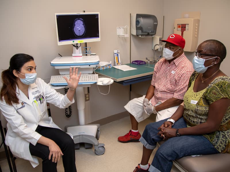 Dr. Nawal Shaikh, left, reviews am image with Marzina Jones and her husband, Steven. Marzina Jones has a rare brain tumor with a BRAF mutation so is receiving a medication that targets that mutation.